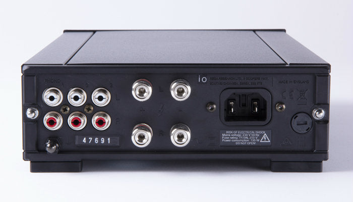 A product image for the rear panel of the Rega io integrated amplifier. This shows three pairs of RCA inputs and the left and right banana socket speaker outputs as well as the power socket