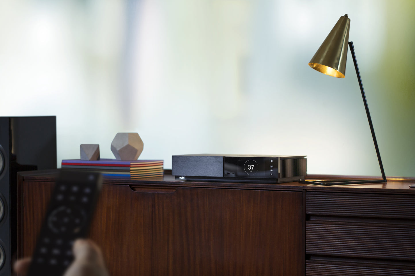 Lifestyle Image of a Naim Uniti Nova All-In-One Player on a sideboard with a lamp shining on it.