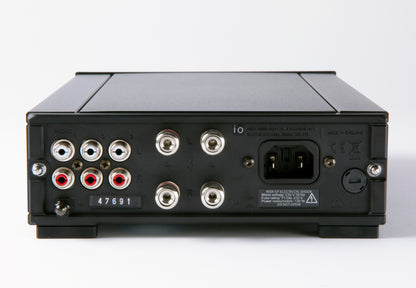 Product image of the rear connection panel of a Rega io integrated amplifier featuring 3 pairs of RCA inputs, two pairs of banana speaker outputs and the power socket.