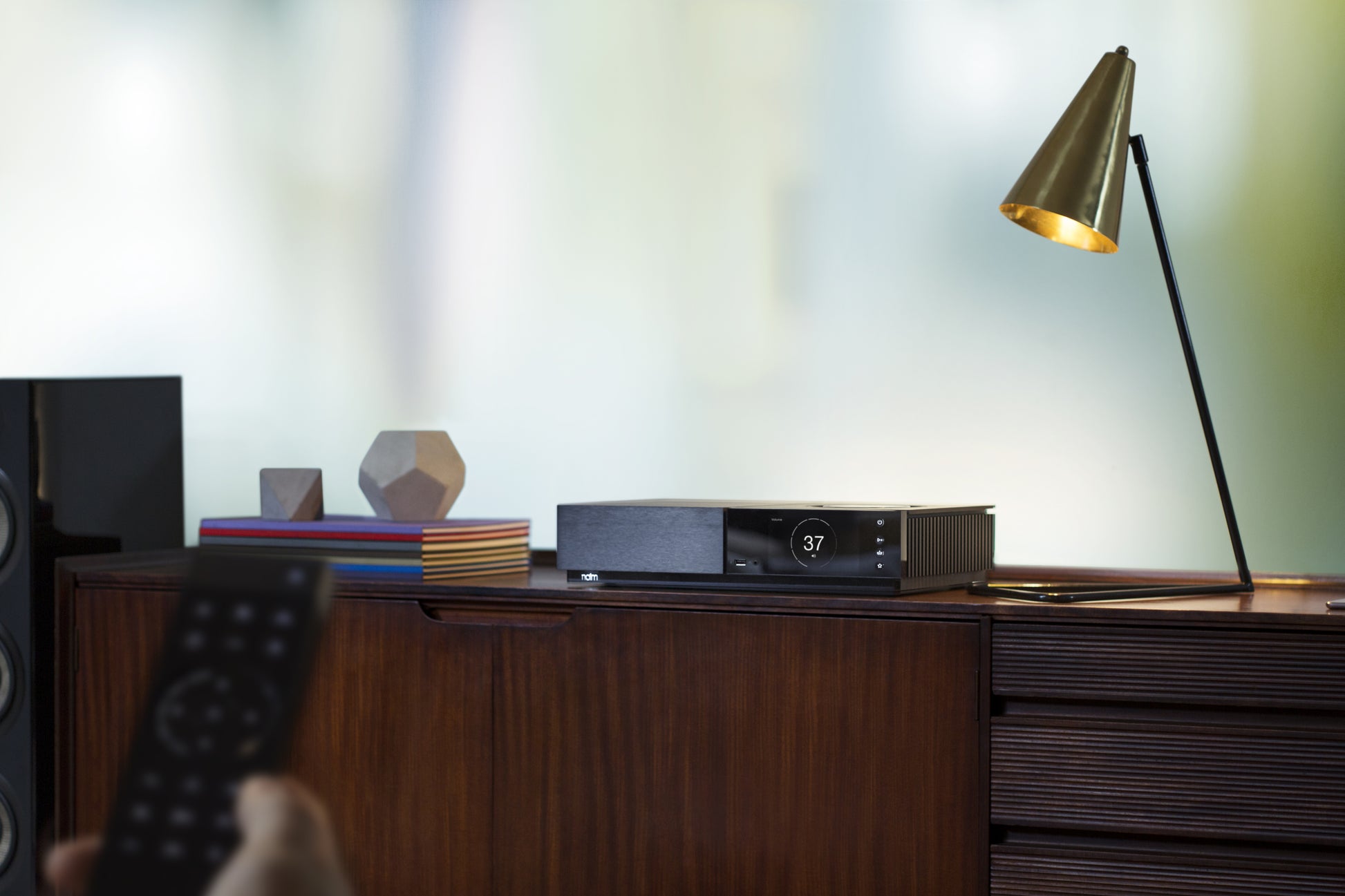 Lifestyle Image of a Naim Uniti Nova All-In-One Player on a sideboard with a lamp shining on it.